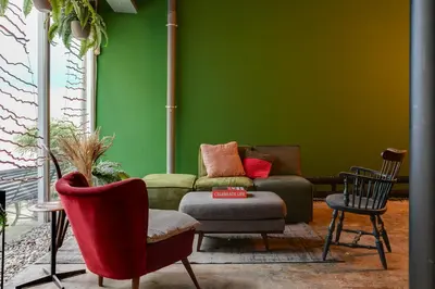 a living room with a green wall with a couch and chairs at ClinkMama in Amsterdam