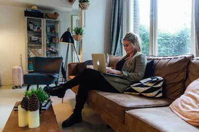a woman sitting on a couch with a laptop at ClinkCoco in Amsterdam