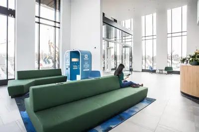 a woman sitting on a green couch in a lobby at MEININGER Hotel Amsterdam Amstel in Amsterdam
