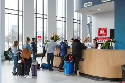 a group of people waiting at a counter in an airport at MEININGER Hotel Amsterdam Amstel in Amsterdam