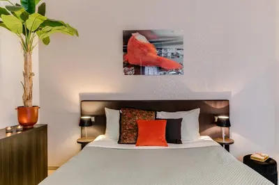 a bedroom with a bed with a red bird on the wall at Brasss Hotel Suites in Haarlem