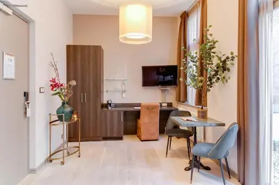 a room with a desk and a table with chairs at Brasss Hotel Suites in Haarlem