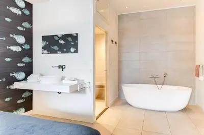a bathroom with a tub and a sink at Brasss Hotel Suites in Haarlem