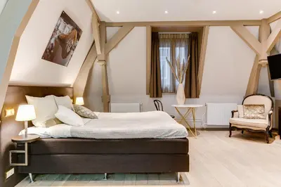 a bedroom with a large bed and a chair at Brasss Hotel Suites in Haarlem