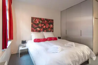 a bedroom with a white bed with red pillows at Here's Lucy in Amsterdam