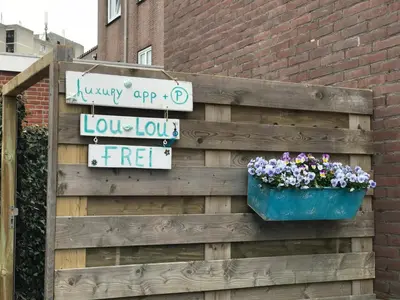 a wooden fence with a pot of flowers and a sign at Lou-Lou in Zandvoort