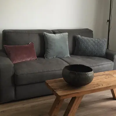 a grey couch with pillows and a wooden coffee table at appartementen zeespiegel in Zandvoort
