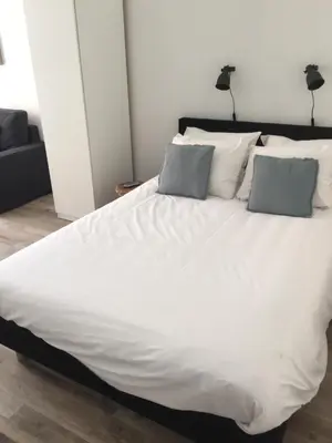 a large white bed with two pillows on it at appartementen zeespiegel in Zandvoort