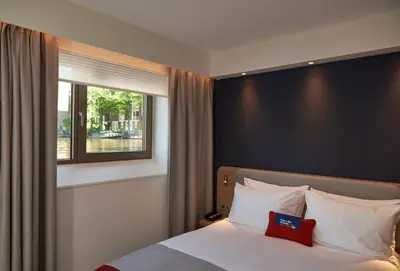 a bedroom with a large bed with a window at Holiday Inn Express Amsterdam - City Hall by IHG in Amsterdam