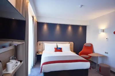 a hotel room with a bed and a red chair at Holiday Inn Express Amsterdam - City Hall by IHG in Amsterdam