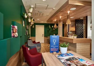 a restaurant with green walls and red chairs and a table at Holiday Inn Express Amsterdam - City Hall by IHG in Amsterdam