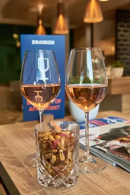 two glasses of wine sitting on a wooden table at Holiday Inn Express Amsterdam - City Hall by IHG in Amsterdam