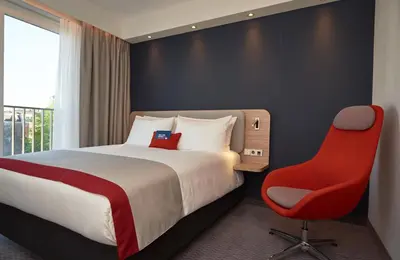 a hotel room with a bed and a red chair at Holiday Inn Express Amsterdam - City Hall by IHG in Amsterdam