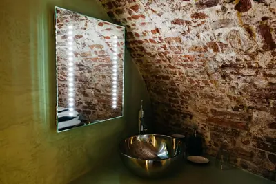 a bathroom with a copper sink and a brick wall at UKI-Hotel in Utrecht