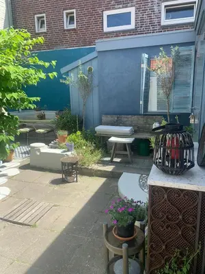 a patio with a bench and a table and flowers at Jopie's Guesthouse in Zandvoort
