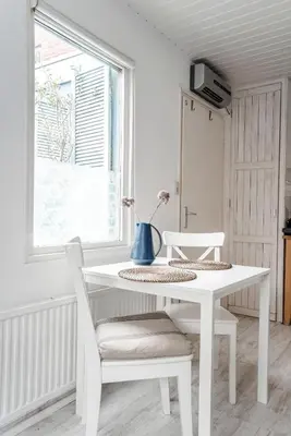 a white table and chairs in a room with a window at Jopie's Guesthouse in Zandvoort