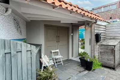 a small house with a wooden door and a chair at Jopie's Guesthouse in Zandvoort