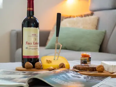 a bottle of wine and cheese on a table with a book at Goditi La Vita in Hem