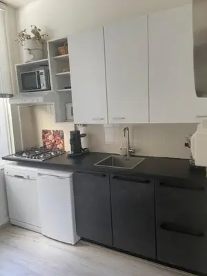a kitchen with white cabinets and a black counter top at SteR Appartement Zandvoort in Zandvoort