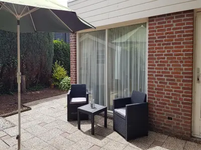 a patio with two chairs and an umbrella at Bungalow in Noordwijkerhout near Lake in Noordwijkerhout