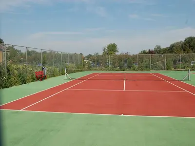 a tennis court with a person sitting in a chair on the court at Bungalow in Noordwijkerhout near Lake in Noordwijkerhout