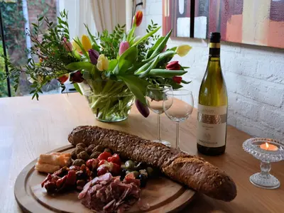a table with a plate of food and a bottle of wine at Bungalow in Noordwijkerhout near Lake in Noordwijkerhout