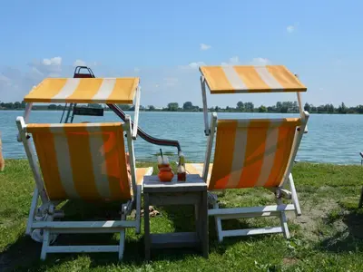 two beach chairs sitting next to a body of water at Bungalow in Noordwijkerhout near Lake in Noordwijkerhout