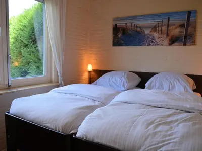 two beds with white sheets in a bedroom with a window at Bungalow in Noordwijkerhout near Lake in Noordwijkerhout