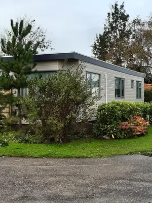 a small white house with trees and bushes at kitty