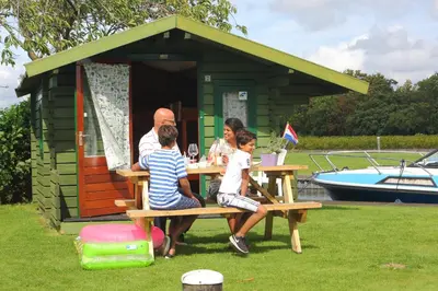 a family sitting at a picnic table in front of a shed at Camping Recreatiepark Aalsmeer in Aalsmeer
