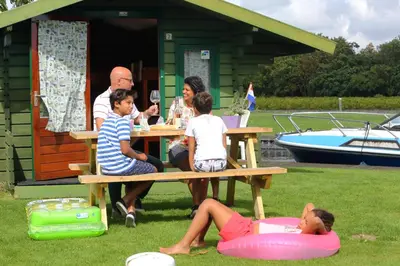 a group of people sitting at a picnic table at Camping Recreatiepark Aalsmeer in Aalsmeer
