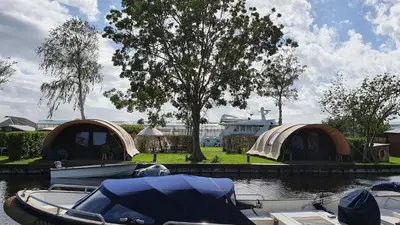a group of tents and a boat in the water at Camping Recreatiepark Aalsmeer in Aalsmeer