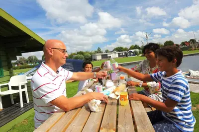 a group of people sitting around a picnic table at Camping Recreatiepark Aalsmeer in Aalsmeer