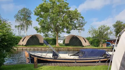 a small boat with two tents on the water at Camping Recreatiepark Aalsmeer in Aalsmeer