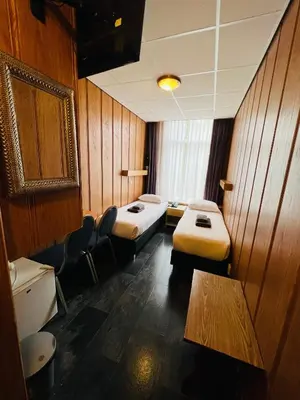 a room with two beds and chairs in it at Hotel Sharm in Amsterdam
