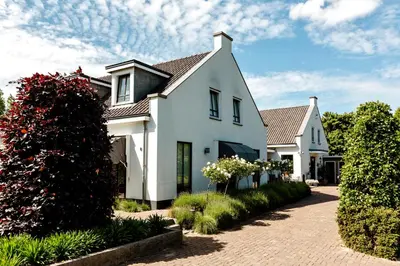 a white house with a brick driveway at B&B Wijk aan Duin in Beverwijk