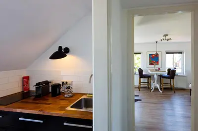 a kitchen with a sink and a table with chairs at B&B Wijk aan Duin in Beverwijk