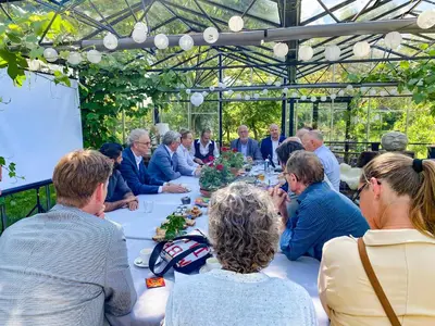 a group of people sitting around a table in a greenhouse at Marenhoeve in Houten