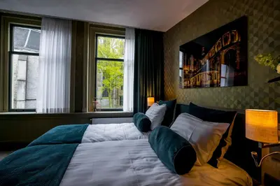 a bedroom with a large bed with pillows and two windows at Slapen bij hofman in Alkmaar