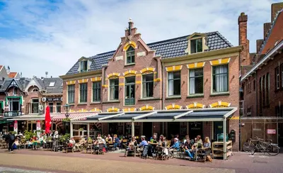 a group of people sitting at tables outside of a building at Slapen bij hofman in Alkmaar