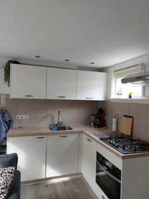 a kitchen with white cabinets and a sink and a stove at Sea Star Egmond aan Zee in Egmond aan Zee