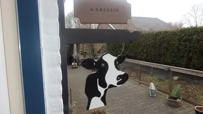 a sign with a cow hanging from a house at B&B Marialin in Wijdewormer