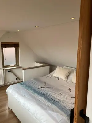 a bedroom with a white bed with a window at Es Vedra in Noordwijk aan Zee
