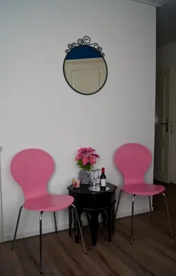 two pink chairs sitting next to a table with a mirror at The Studio Guesthouse in Volendam