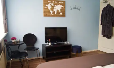 a living room with a flat screen tv and two chairs at The Studio Guesthouse in Volendam