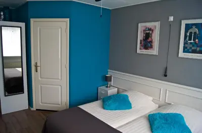 a bedroom with blue walls and a bed with blue pillows at The Studio Guesthouse in Volendam