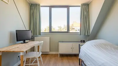 a bedroom with a bed and a desk with a computer at Goudkust 3 'At Sea' in Bergen