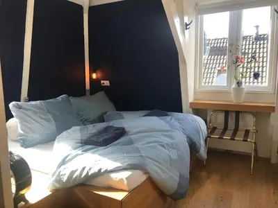 a bedroom with a bed with blue sheets and a window at B&B Numero 14 in Amsterdam