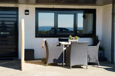 a table and chairs on a patio with a window at B&B Zeespiegel in Zandvoort