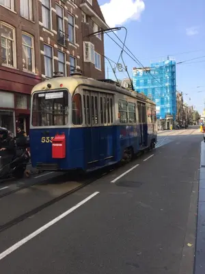 a blue and white tram driving down a city street at Het Kabinet in Amsterdam